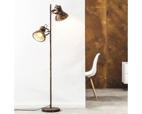 Golvlampa med två strålkastare i industriell design bredvid en stol