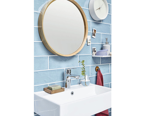 Modernt badrum med handfat, spegel, blandare och blått kakel