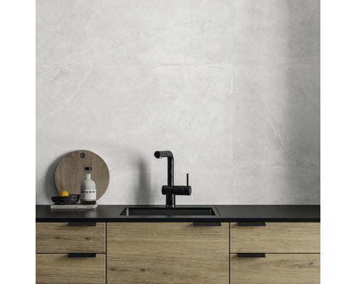 Ljust kök med väggplattor i marmorlook, diskho och underskåp i trä.