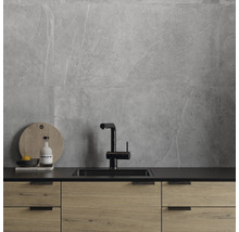 Köksscen med grå väggplattor, diskho och köksskåp i trä.