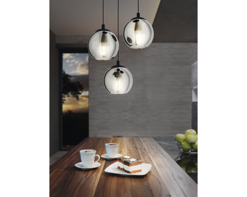 Scen med tre runda hängande glaslampor ovanför ett träbord