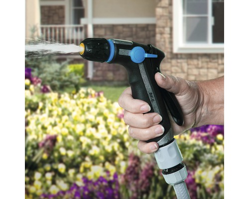 En hand håller en trädgårdsspruta och vattnar växter.