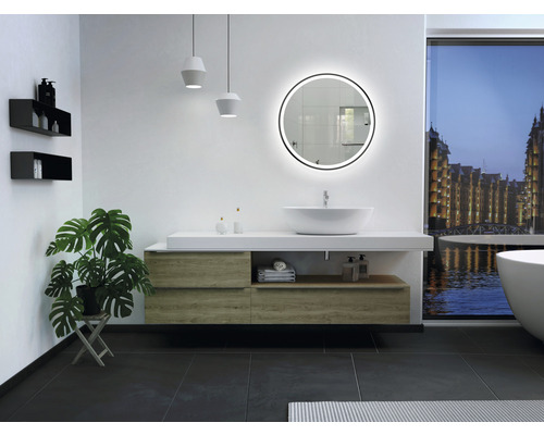 Modernt badrum med tvättställ, rund spegel med belysning, hyllor och krukväxt