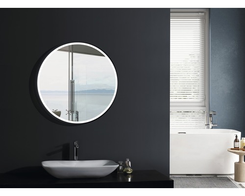 Badrum med rund spegel, handfat, badkar och fönster