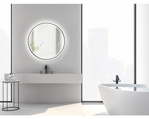 Ljust badrum med rund spegel, handfat, badkar och sidobord