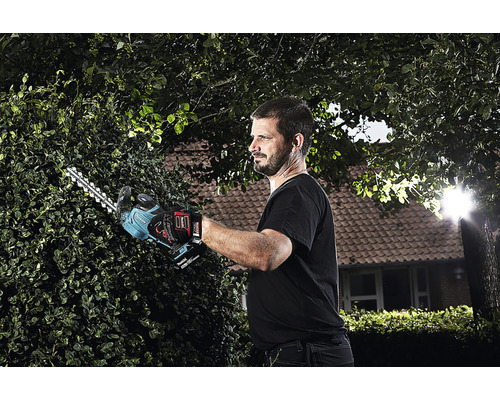 Man klipper häck med en batteridriven häcksax