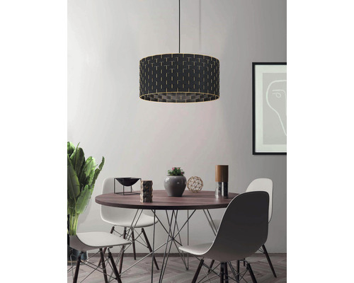 Matsal med matbord, stolar och en svart hänglampa med dekorativt mönster