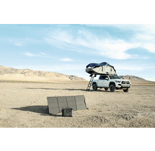 Campingutrustning med solpanel och bärbar kraftstation bredvid en pickup med taktält i öknen