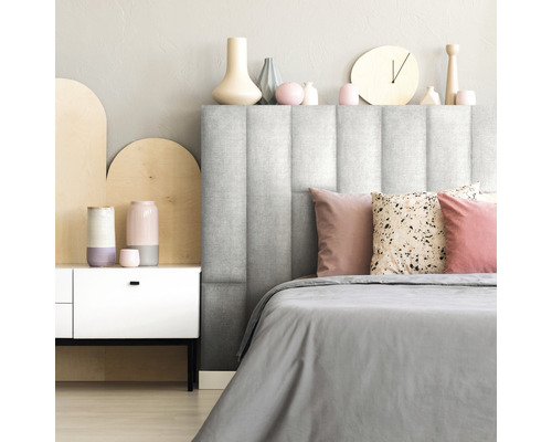 Sovrum med vadderad sänggavel, sängkläder och dekorativa element.