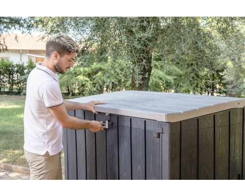 Man öppnar en trädgårdskista med lock utomhus