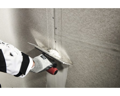 Applicering av armeringsväv på en vägg med en spackel.