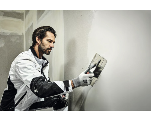 Hantverkare jämnar ut en vägg med en murslev.