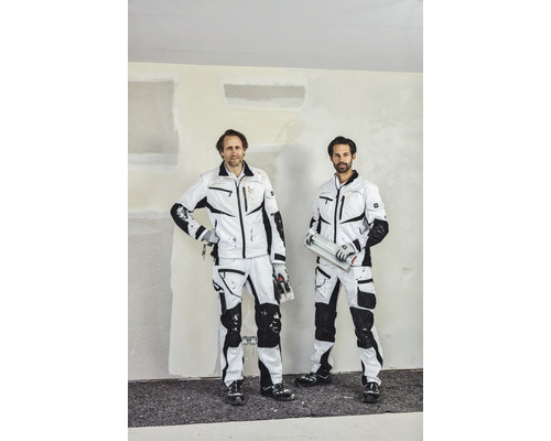 Två hantverkare i arbetskläder framför en putsad vägg.