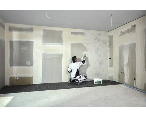 Interiör med hantverkare som spacklar en vägg