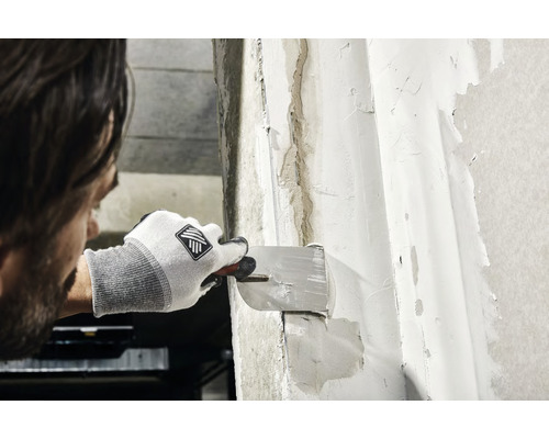 Man spacklar en vägg med en spackel.
