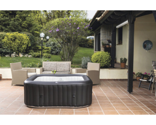 Uppblåsbar bubbelpool på en uteplats med trädgårdsmöbler och växter