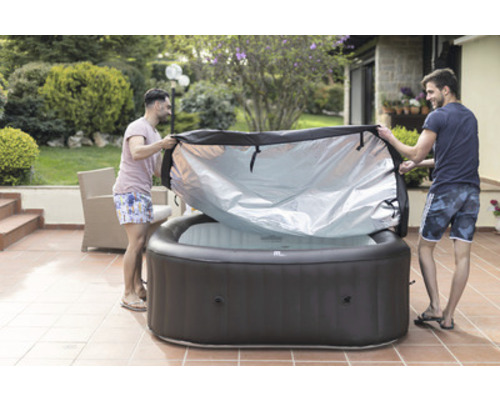 Två män tar bort skyddet från en uppblåsbar jacuzzi i trädgården.