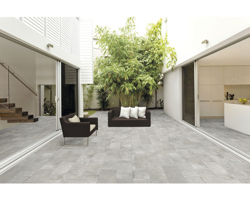 Ljus terrass med grå golvplattor, sittmöbler och växter