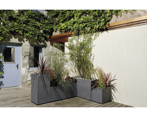 Tre grå krukor i stengods med plantering utomhus.