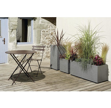 Trädgårdsscen med bord, stol och planterade planteringslådor på en terrass