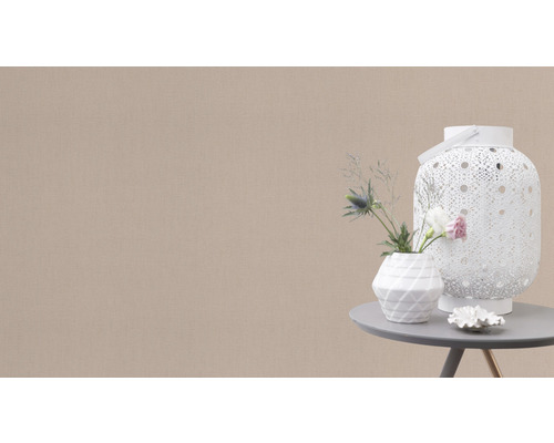 Dekorativ scen med en vit lykta, en vas med blommor och en liten dekoration på ett bord