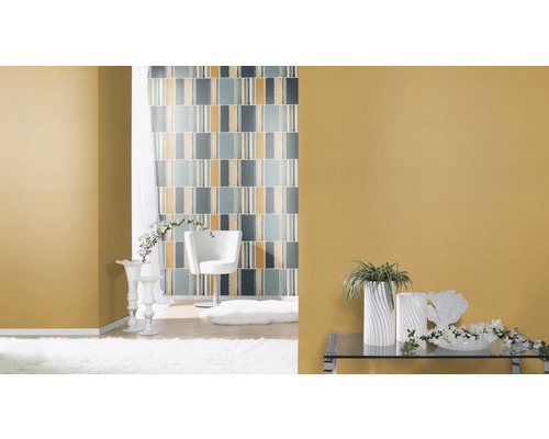 Ljust vardagsrum med mönstrad tapet, fåtölj och dekorationer