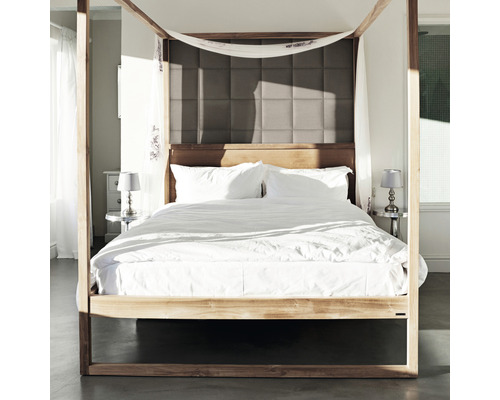 Säng med himmel, sängkläder och vadderad sänggavel i sovrummet