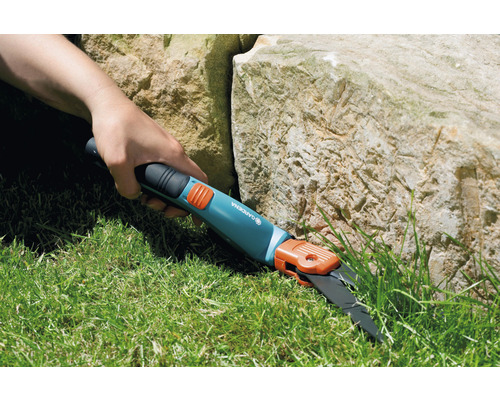 Person klipper gräs med en Gardena grässax.