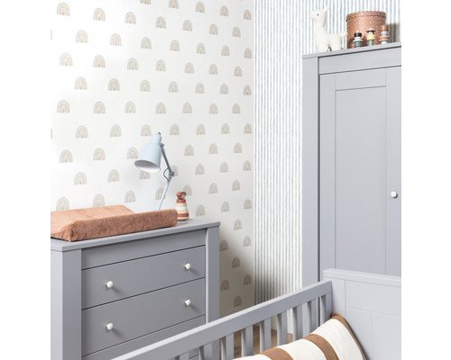 Ett barnrum med en skötbyrå, en garderob och en vägg med ett regnbågsmönster.