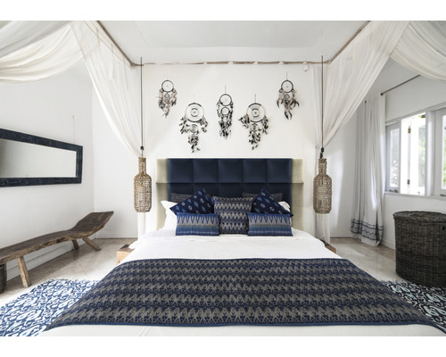 Sovrum med dubbelsäng, sänglampor, drömfångare och blå textilier