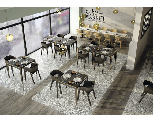 Interiör av en restaurang med bord och stolar på ett mönstrat klinkergolv.