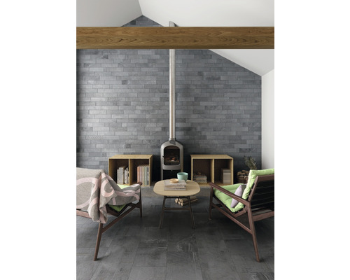 Vardagsrum med tegelvägg, vedeldad kamin och sittgrupp.