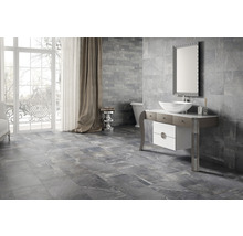 Modernt badrum med grå kakel på vägg och golv, tvättställsskåp, spegel och badkar.