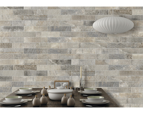 Väggdekoration med ljusa, långsträckta plattor i stenlook ovanför ett matbord.