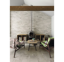 Vardagsrum med eldstad, klinkergolv, två fåtöljer och ett litet bord