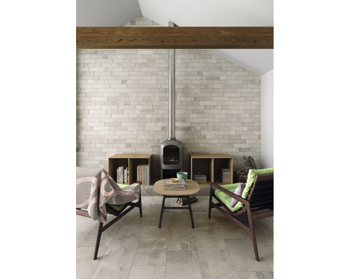 Vardagsrum med eldstad, klinkergolv, två fåtöljer och ett litet bord