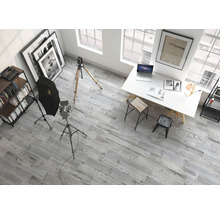 Interiörbild av en studio med fotoutrustning, skrivbord, hyllor och grått trägolv