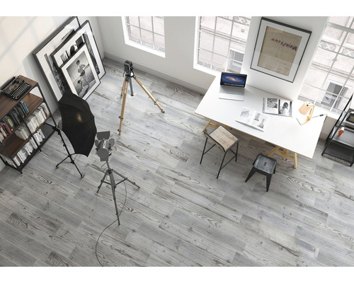 Interiörbild av en studio med fotoutrustning, skrivbord, hyllor och grått trägolv