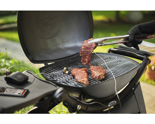 Grillscen med biffar på grillen och grilltång med en biff