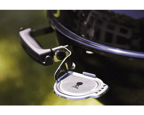 Detaljvy av en klotgrill med öppen askbehållare och Weber-logotyp