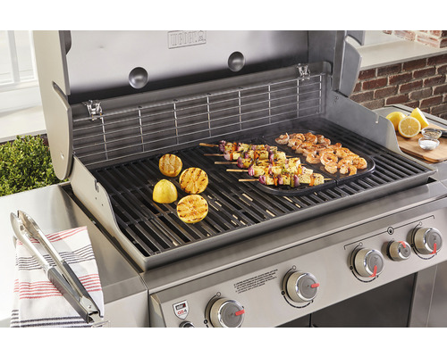 Weber grill med grillad mat och citroner på grillen