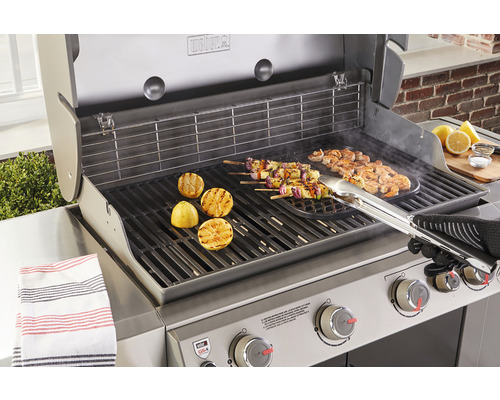 Weber grill med grillad mat som citroner, spett och räkor