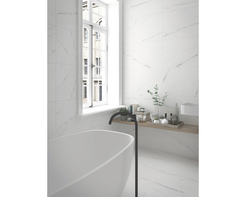 Ljust badrum med kakel i marmorlook, badkar och fönster