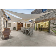 Uteplats med stengolv, matbord och solsegel