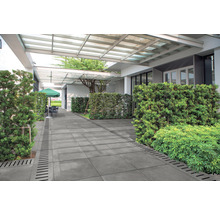 Utomhusområde med betongsten, dräneringsrännor och planteringar