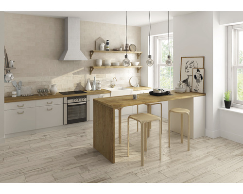 Ljust kök med klinkergolv, köksdel, matplats och fönster för naturligt ljus.