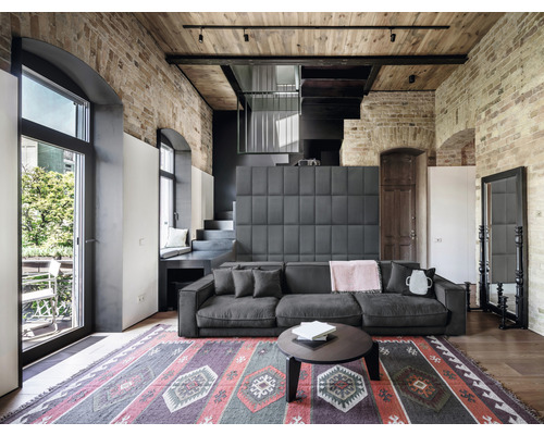 Vardagsrum med soffa, matta och tegelvägg