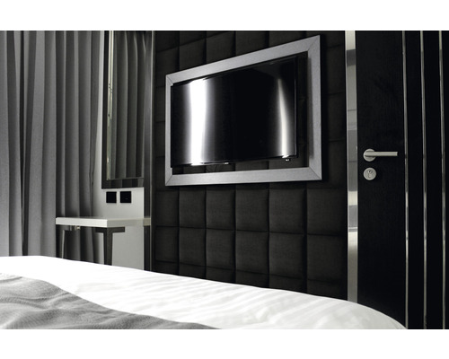 Sovrum med vadderad vägg, tv och sängbord