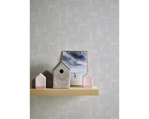 Scen med en trähylla på vilken det står dekorativa hus och en clipboards framför en mönstrad tapet.
