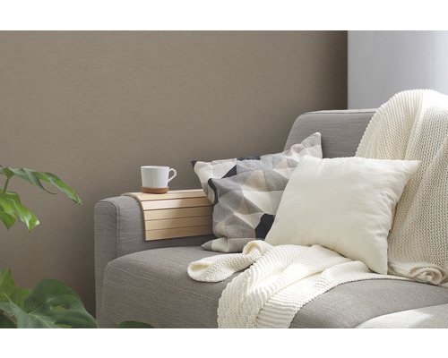 Grå soffa med kuddar, en mugg och en trähylla.
